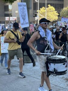 Marchers on the street include a drummer with Palestinian keffiyeh